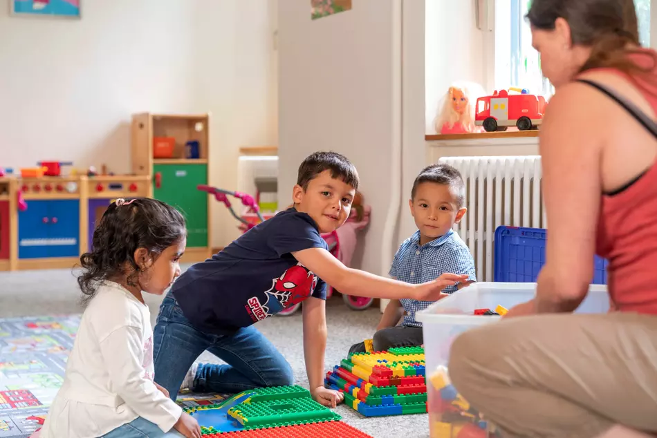 Laughing children playing on the floor – image from a project by the NGO HEKS.