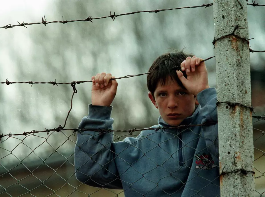 A boy holding onto a barbed wire fence during the Kosovo conflict in 1999 – symbol of hardship and hope supported by Swiss Solidarity.