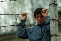 A boy holding onto a barbed wire fence during the Kosovo conflict in 1999 – symbol of hardship and hope supported by Swiss Solidarity.