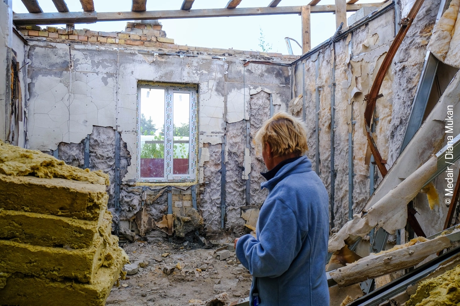 A person gazes at the collapsed walls of a destroyed house - damage from the war in Ukraine and urgent need for reconstruction.