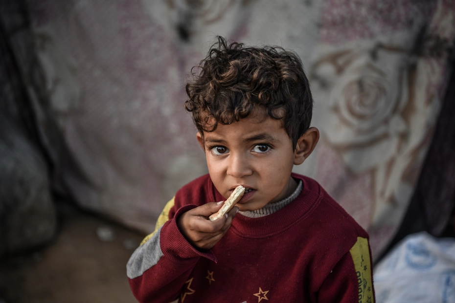 A little boy eats a piece of bread - donations provide essential food aid in times of war.