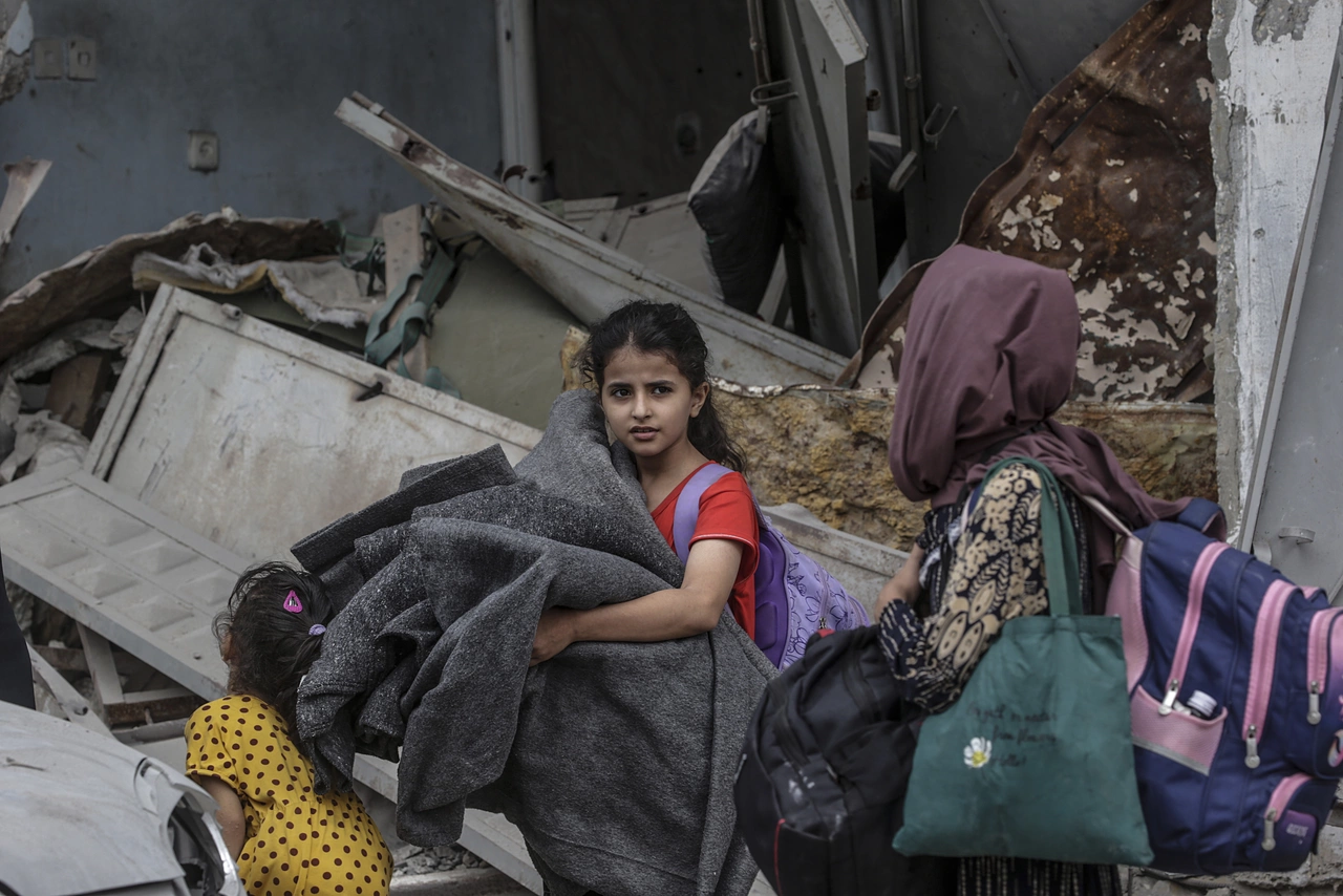 A young girl in Gaza with her belongings - forced to flee, she needs urgent help.