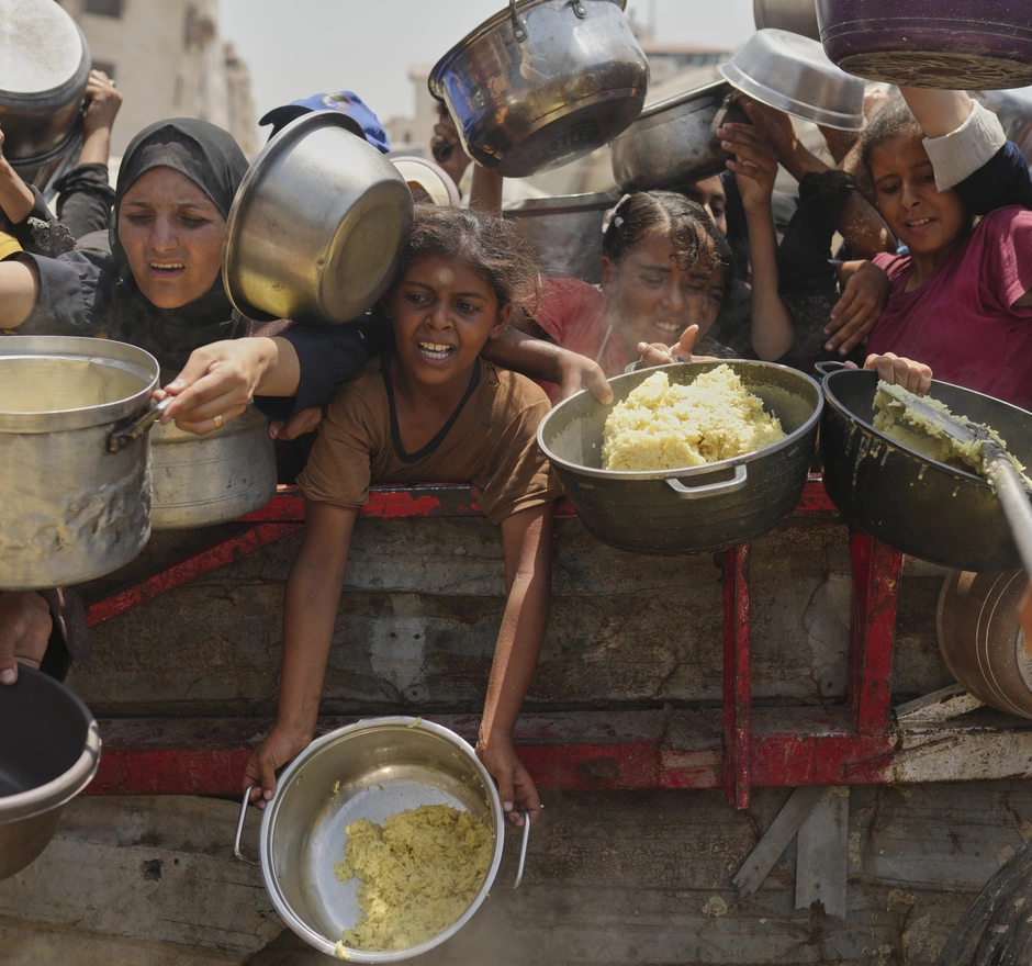 Palestinians struggle to get donated food at a community kitchen in Gaza City, northern Gaza Strip, Saturday, Aug. 16, 2025.