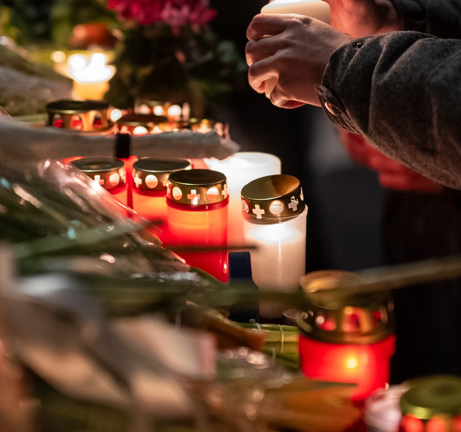 A person lights candles for a mourning altar.