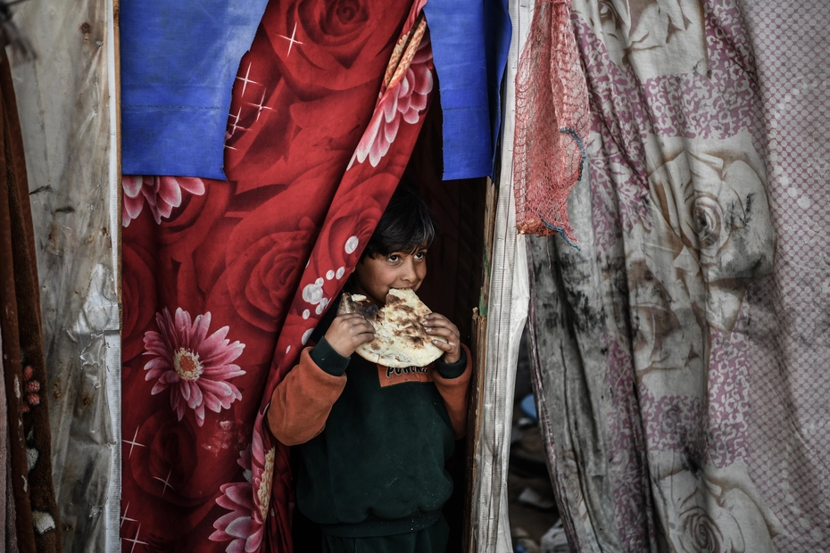 A boy in Gaza eats bread - donations provide essential food aid in a crisis zone.