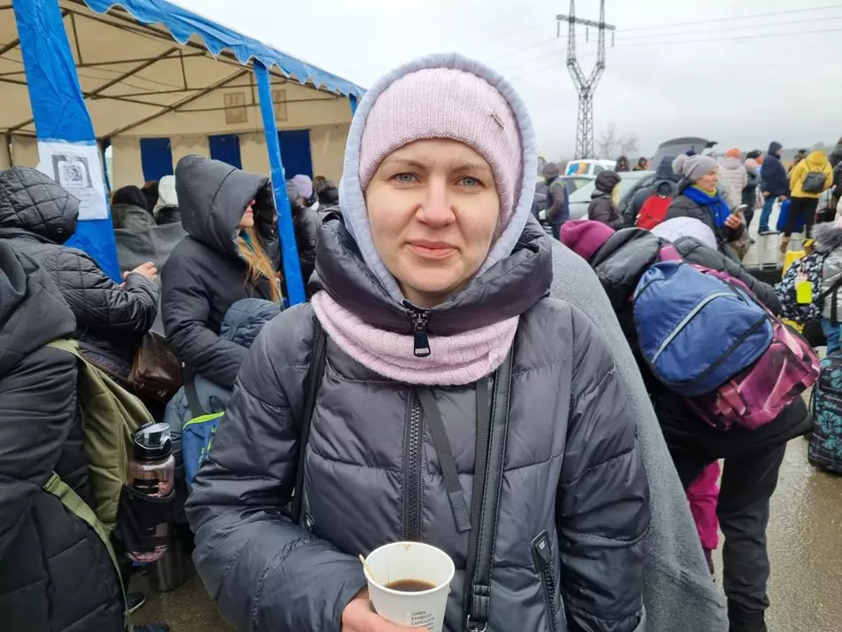 A woman in a winter coat holds a cup of hot drink at a refugee aid center in Ukraine - a gesture of hope and support.
