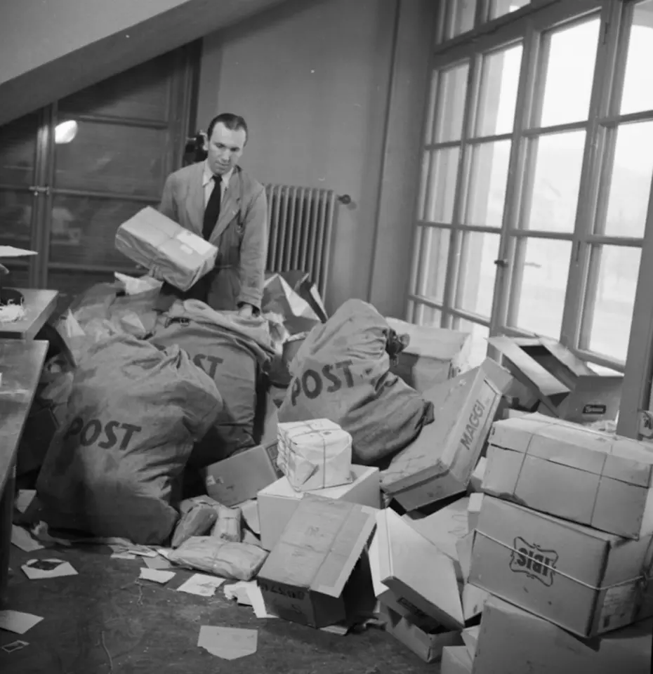 A man sorts large sacks of letters and packages – symbolising Swiss Solidarity’s early international efforts after the war.